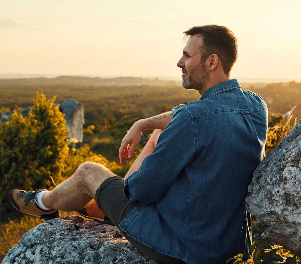 Man sitting on a hilltop at sunset – online psychiatry in Troy, MI